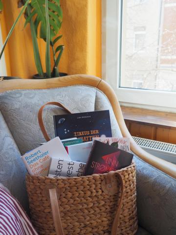 Eine große Tasche gefüllt mit Büchern, die auf einem Sessel steht
